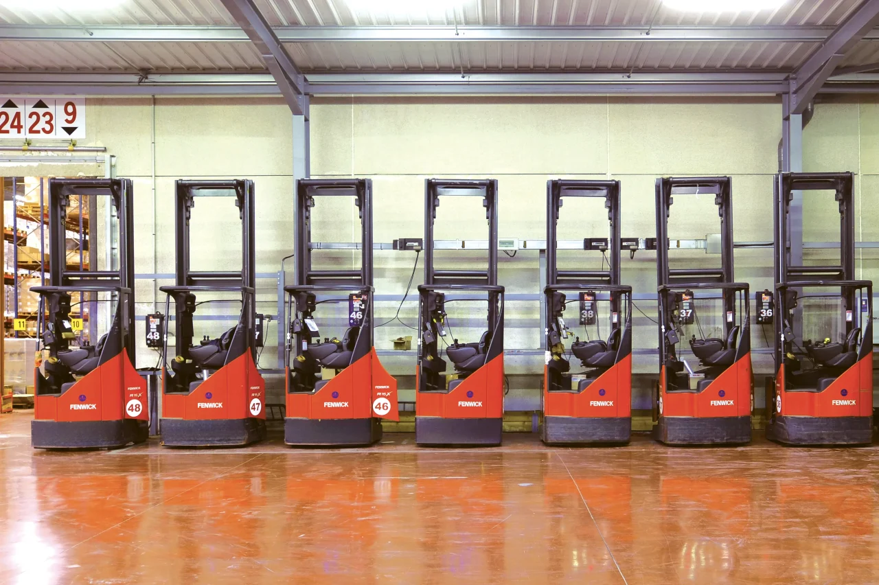 Chariots élévateurs électriques alignés dans un entrepôt logistique Vectura Logistique