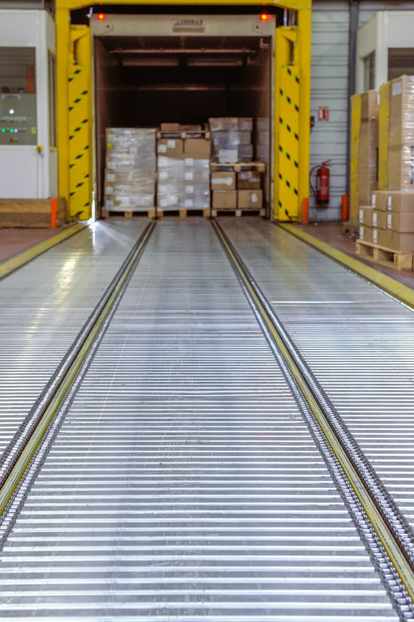 Zone de chargement logistique avec convoyeur et palettes prêtes à expédition
