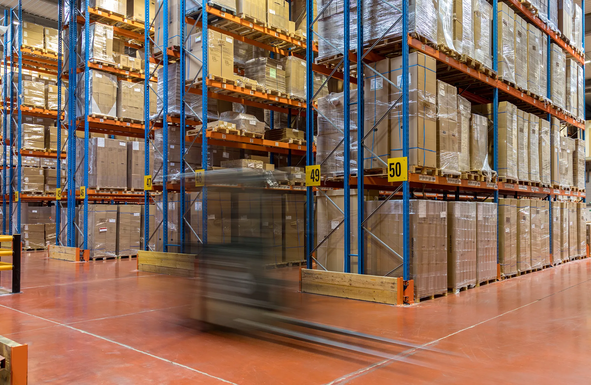 Allées de stockage avec palettes et chariot de manutention en mouvement dans l'entrepôt Vectura Logistique